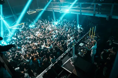 Crowd of people standing around a DJ booth