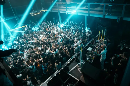 Crowd of people standing around a DJ booth