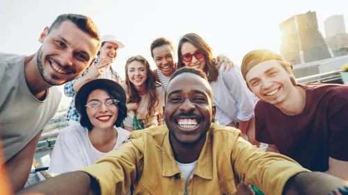 Diverse group of friends smiling together for a selfie outdoors