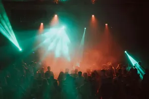 Crowd dancing under colourful stage lights at a night event